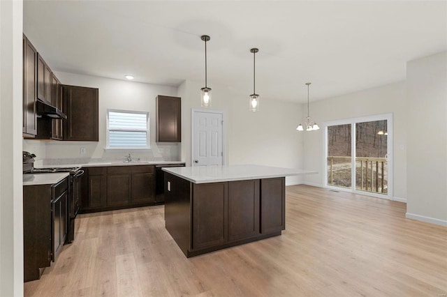 kitchen with black appliances, light wood-style floors, dark brown cabinets, under cabinet range hood, and a kitchen island