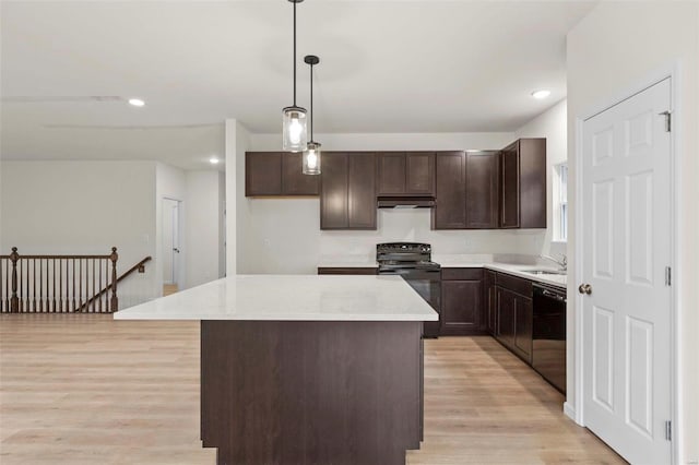 kitchen featuring black appliances, under cabinet range hood, a sink, light wood-type flooring, and dark brown cabinetry