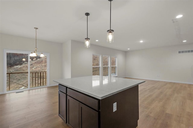 kitchen with light wood-style flooring, dark brown cabinets, light countertops, pendant lighting, and recessed lighting