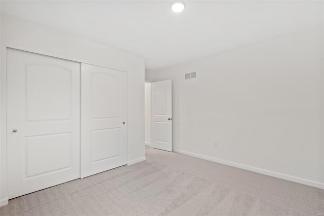 unfurnished bedroom with light carpet, a closet, and baseboards