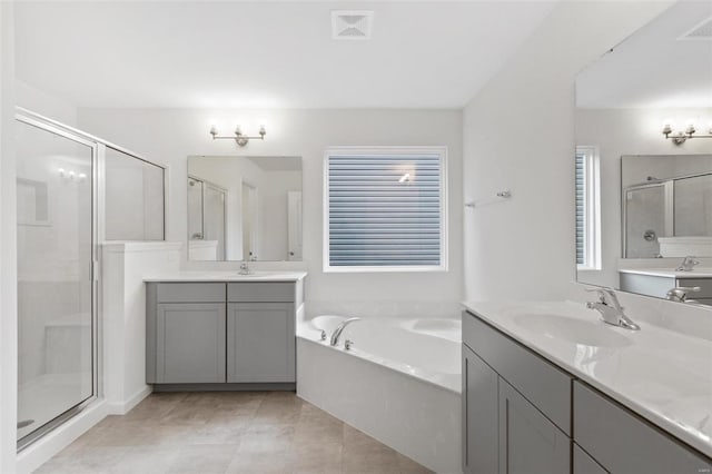full bath with a shower stall, a bath, two vanities, and tile patterned floors