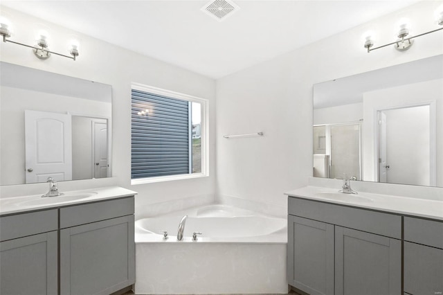 bathroom featuring a shower stall, a bath, and two vanities