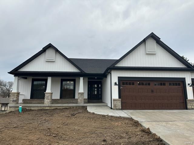 view of front of home featuring a porch, concrete driveway, an attached garage, and stone siding