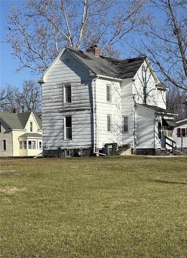 328 W Orrick, La Plata, MO 63549 - view of side of home with entry steps, a chimney, a lawn, and cooling unit