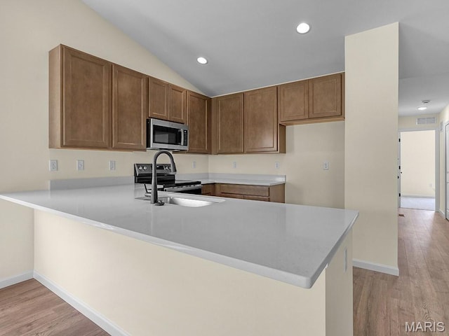 3136 White Pine Dr, Imperial, MO 63052 - kitchen featuring stainless steel microwave, range with electric stovetop, a peninsula, light countertops, and light wood-style floors