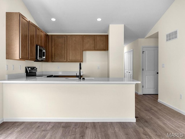 3136 White Pine Dr, Imperial, MO 63052 - kitchen featuring stainless steel microwave, electric range oven, a peninsula, light countertops, and lofted ceiling