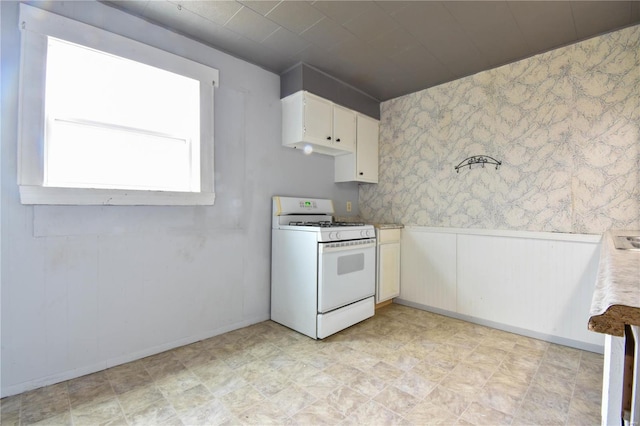 1103 S Madison St, Gillespie, IL 62033 - kitchen featuring white range with gas cooktop, a wainscoted wall, light countertops, white cabinetry, and wallpapered walls