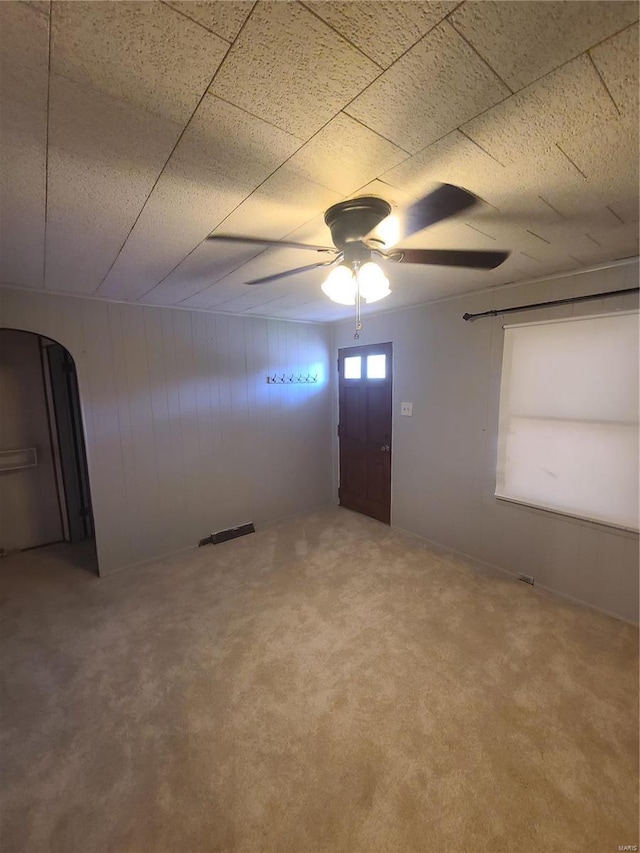 2709 Ralph St, Granite City, IL 62040 - carpeted empty room with arched walkways, a ceiling fan, and wooden walls
