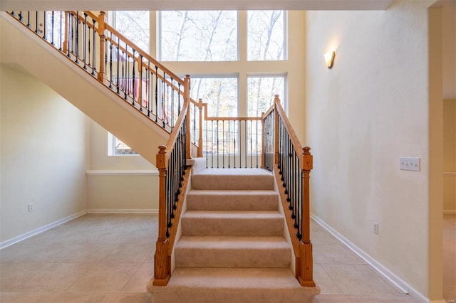 814 Marti Dr, Rolla, MO 65401 - staircase with tile patterned floors, baseboards, and a towering ceiling