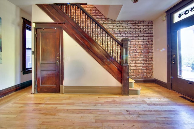 3834 De Tonty St, Saint Louis, MO 63110 - foyer featuring stairway, brick wall, light wood finished floors, and baseboards