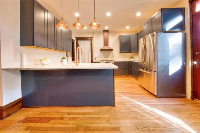 3834 De Tonty St, Saint Louis, MO 63110 - kitchen featuring freestanding refrigerator, a peninsula, wall chimney range hood, light stone countertops, and light wood finished floors