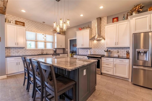 101 Lauren Grace Ct, Elsberry, MO 63343 - kitchen featuring stainless steel appliances, wall chimney range hood, a sink, a kitchen island, and a breakfast bar