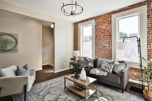 4211 Norfolk Ave, Saint Louis, MO 63110 - living room featuring wood finished floors, a chandelier, brick wall, and baseboards