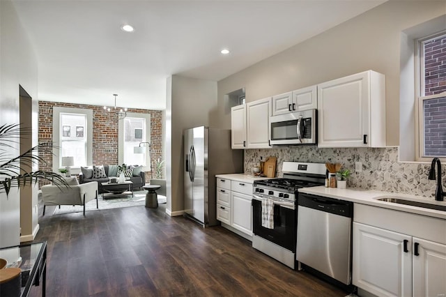 4211 Norfolk Ave, Saint Louis, MO 63110 - kitchen featuring stainless steel appliances, a sink, light countertops, white cabinetry, and backsplash