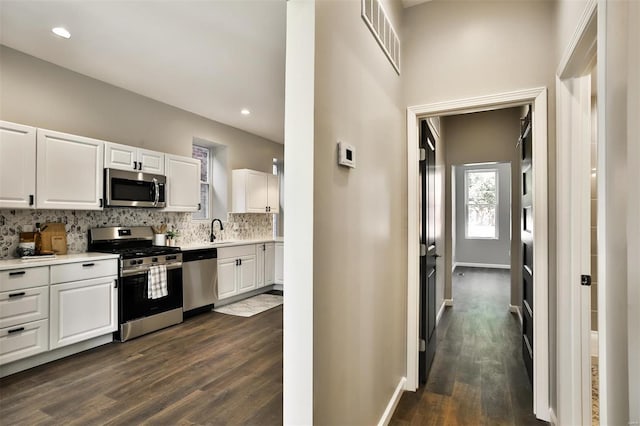 4211 Norfolk Ave, Saint Louis, MO 63110 - kitchen featuring appliances with stainless steel finishes, dark wood-style floors, white cabinets, tasteful backsplash, and light countertops