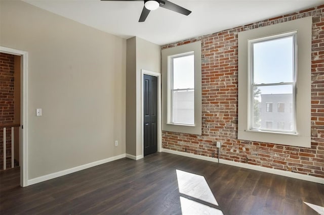 4211 Norfolk Ave, Saint Louis, MO 63110 - unfurnished room with baseboards, brick wall, a ceiling fan, dark wood-style floors, and healthy amount of natural light