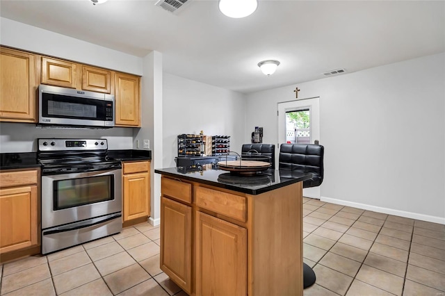 950 E Rue De La Banque Unit L1, Creve Coeur, MO 63141 - kitchen featuring stainless steel appliances, light tile patterned floors, dark countertops, and a center island