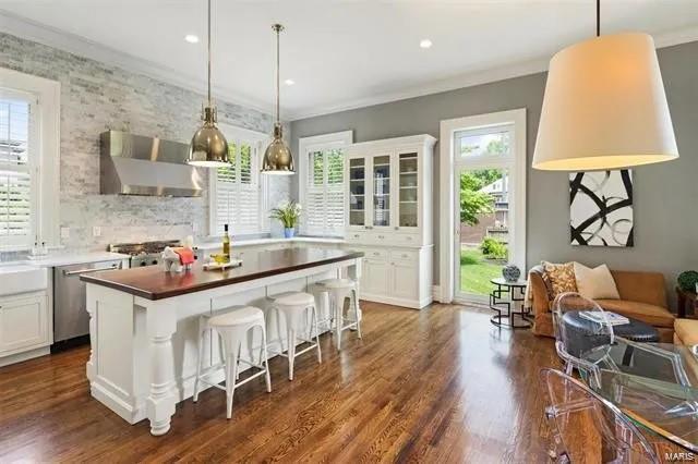 4969 Pershing Pl Unit 1, Saint Louis, MO 63108 - kitchen featuring wall chimney range hood, stainless steel dishwasher, plenty of natural light, dark wood-style floors, and ornamental molding