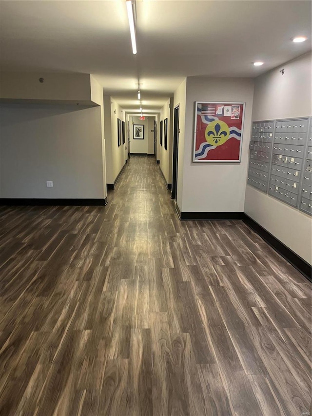 unfurnished room with mail area, dark wood-style floors, and baseboards