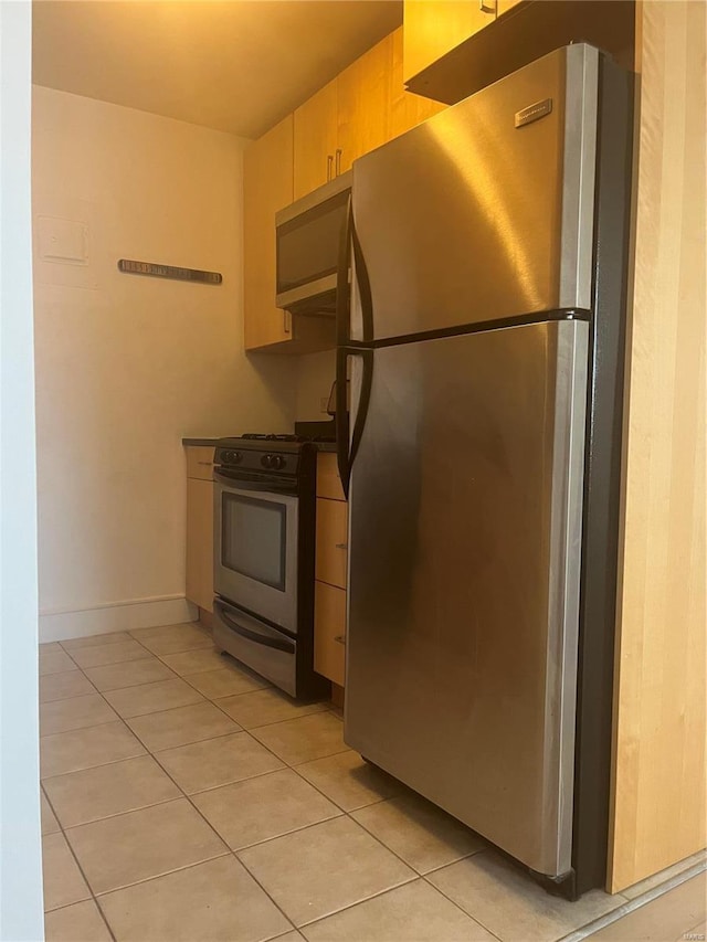kitchen with appliances with stainless steel finishes, light tile patterned flooring, dark countertops, and baseboards
