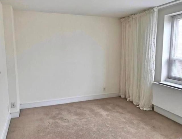 spare room with light carpet and baseboards