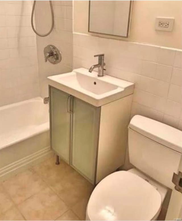 bathroom featuring tile walls, toilet, vanity, tile patterned floors, and tub / shower combination