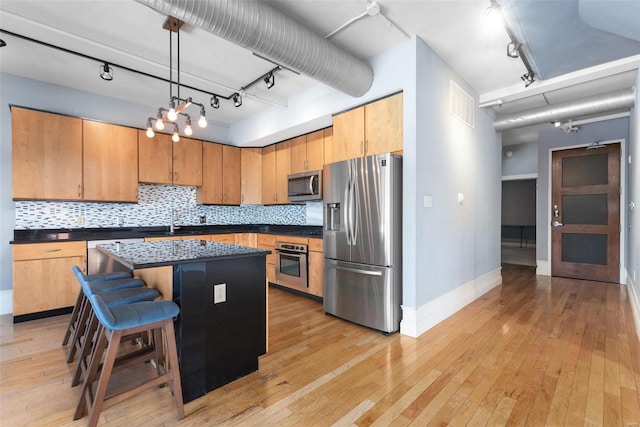 4901 Washington Blvd Unit 2C, Saint Louis, MO 63108 - kitchen with stainless steel appliances, track lighting, dark countertops, decorative backsplash, and light wood-style floors