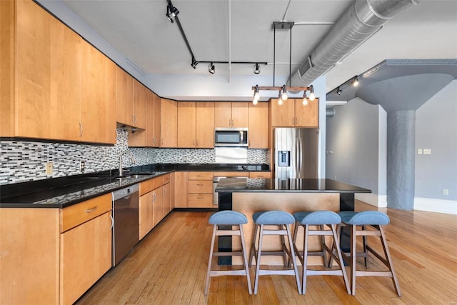 4901 Washington Blvd Unit 2C, Saint Louis, MO 63108 - kitchen featuring appliances with stainless steel finishes, a sink, track lighting, light wood-type flooring, and dark countertops