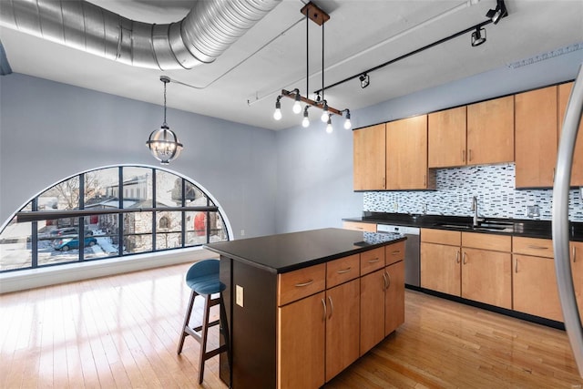 4901 Washington Blvd Unit 2C, Saint Louis, MO 63108 - kitchen featuring a sink, dark countertops, light wood-style floors, dishwasher, and decorative backsplash