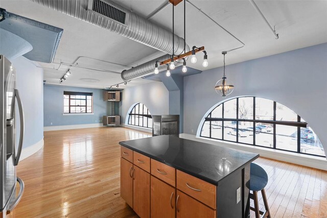 4901 Washington Blvd Unit 2C, Saint Louis, MO 63108 - kitchen featuring stainless steel fridge, dark countertops, a center island, and light wood-style floors