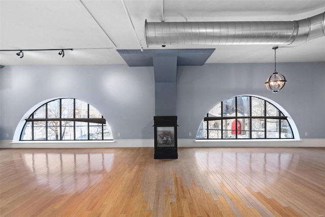 4901 Washington Blvd Unit 2C, Saint Louis, MO 63108 - unfurnished living room with track lighting, hardwood / wood-style floors, baseboards, and a multi sided fireplace