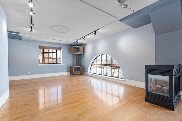 4901 Washington Blvd Unit 2C, Saint Louis, MO 63108 - unfurnished living room with track lighting, wood finished floors, a multi sided fireplace, and baseboards
