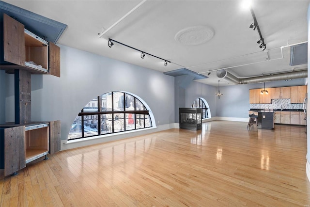 4901 Washington Blvd Unit 2C, Saint Louis, MO 63108 - unfurnished living room featuring rail lighting, light wood-style floors, baseboards, and a sink