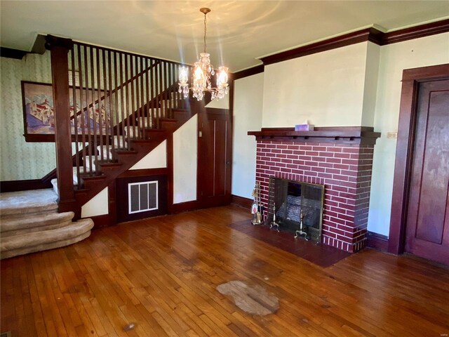 101 E Cedar St, Bertrand, MO 63823 - unfurnished living room with ornamental molding, stairs, hardwood / wood-style flooring, baseboards, and a brick fireplace