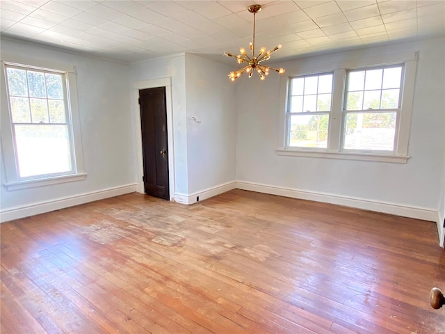 101 E Cedar St, Bertrand, MO 63823 - unfurnished room with healthy amount of natural light, a chandelier, light wood finished floors, and baseboards