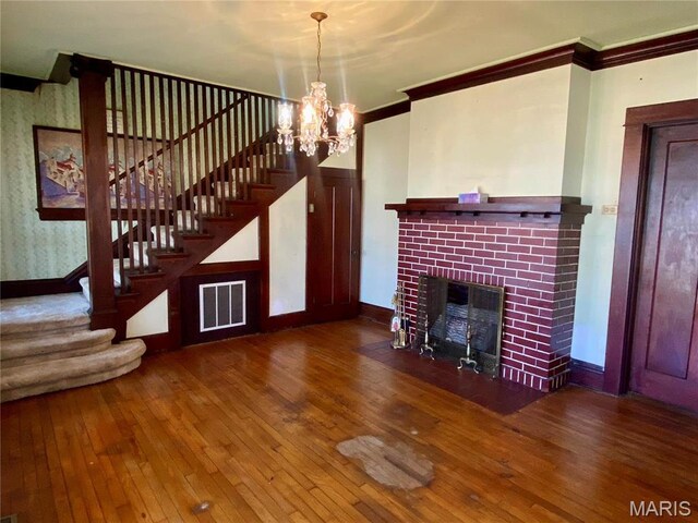 101 E Cedar St, Bertrand, MO 63823 - unfurnished living room with stairs, crown molding, wood-type flooring, a chandelier, and a fireplace