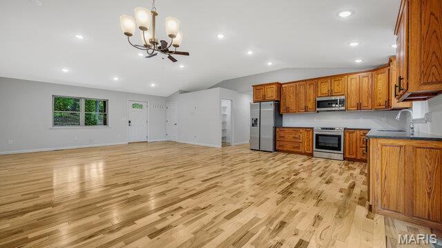 18305 Joerling Ln, Marthasville, MO 63357 - kitchen with appliances with stainless steel finishes, vaulted ceiling, brown cabinetry, a chandelier, and a sink