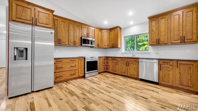 18305 Joerling Ln, Marthasville, MO 63357 - kitchen with appliances with stainless steel finishes, brown cabinetry, light wood finished floors, a sink, and vaulted ceiling