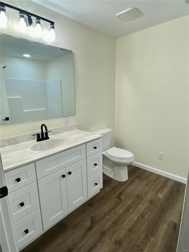 317 E Cypress St, Charleston, MO 63834 - bathroom featuring wood finished floors, toilet, vanity, and baseboards