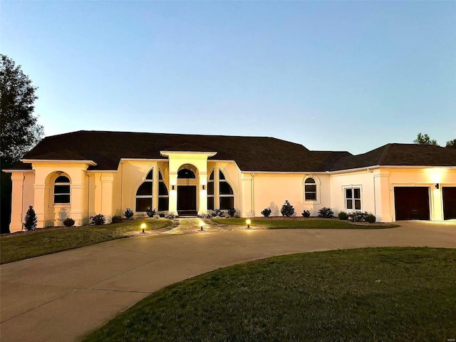 237 Kensington Ln, Cape Girardeau, MO 63701 - view of front of house with curved driveway, stucco siding, a front yard, and an attached garage