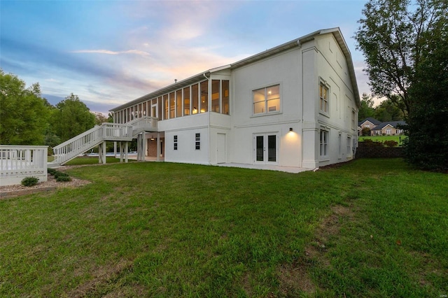 237 Kensington Ln, Cape Girardeau, MO 63701 - back of house at dusk with stucco siding, a lawn, stairway, and a deck