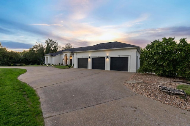 237 Kensington Ln, Cape Girardeau, MO 63701 - property exterior at dusk with driveway, an attached garage, stucco siding, and a lawn