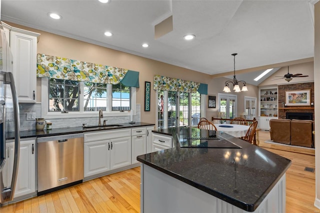 1125 N Franklin St, Litchfield, IL 62056 - kitchen featuring stainless steel dishwasher, a sink, black electric cooktop, a fireplace, and a kitchen island