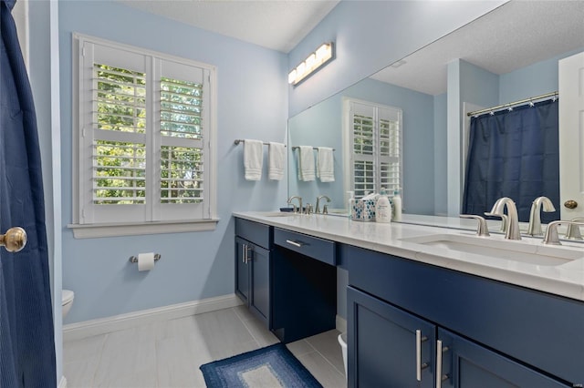 1125 N Franklin St, Litchfield, IL 62056 - full bath with healthy amount of natural light, toilet, double vanity, baseboards, and a textured ceiling