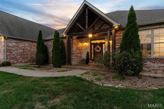 view of front facade featuring brick siding, a lawn, and a shingled roof