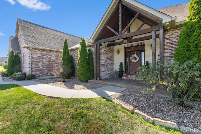 view of front of property featuring brick siding, a front yard, and a shingled roof
