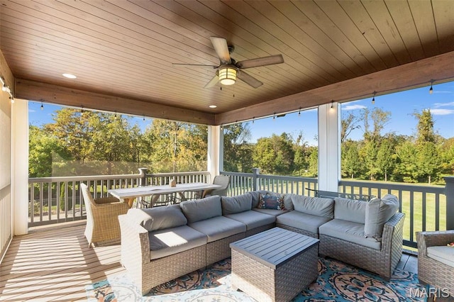 wooden deck with an outdoor hangout area, ceiling fan, outdoor dining area, and view of scattered trees
