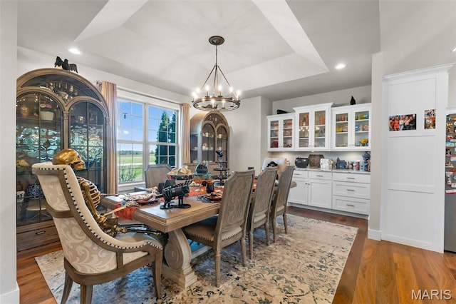 dining space with a chandelier, a tray ceiling, wood finished floors, and recessed lighting