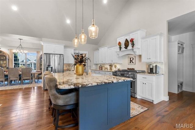 kitchen with high end stainless steel range, white cabinets, a spacious island, light stone countertops, and high vaulted ceiling