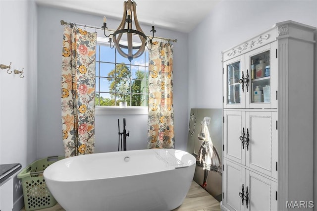 bathroom featuring a soaking tub and a chandelier